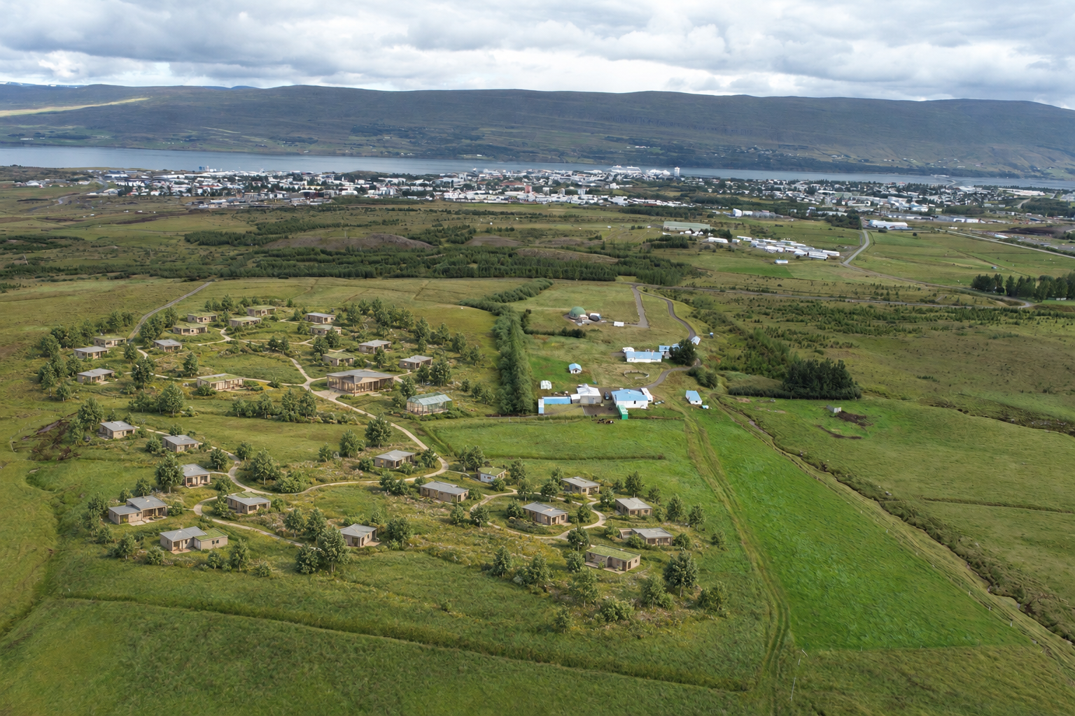 Hugmynd að timburhúsum, gönguleiðum, samkomuhúsi og gróðurhúsi felld inn á loftmynd af Hesjuvöllum